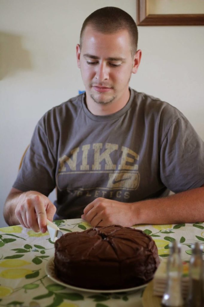 man cutting chocolate cake
