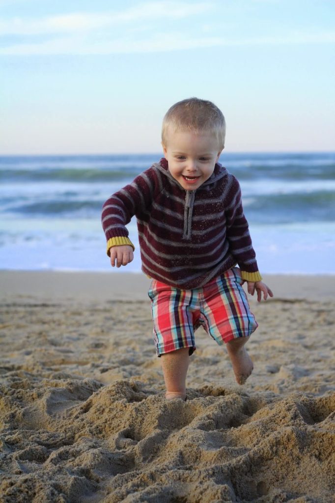 toddler boy running in sand