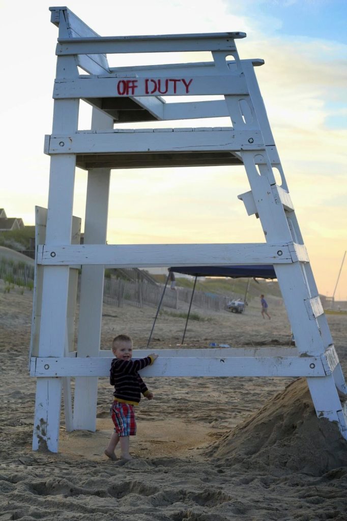 toddler standing next to lifeguard post