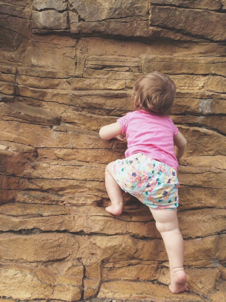 baby girl climbing up rocks