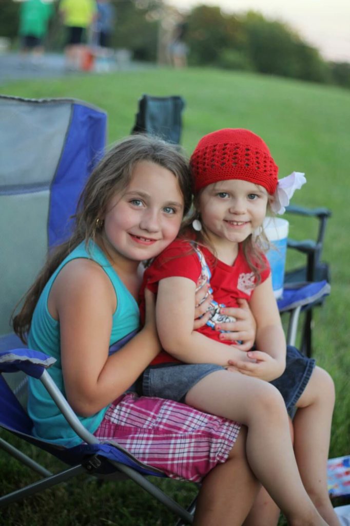 two girls sitting on lawn chair