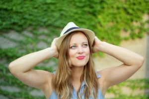 young woman holding hat