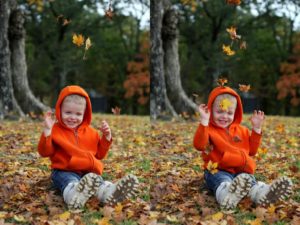 cute toddler boy sitting in leaves and laughing