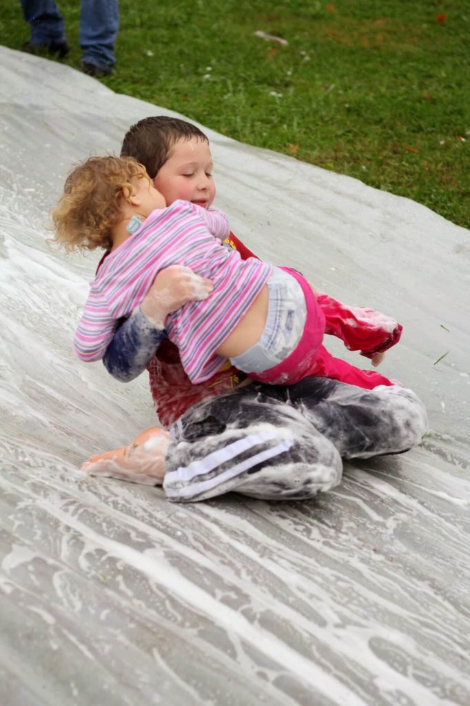 boy and girl sliding down soapy water slide