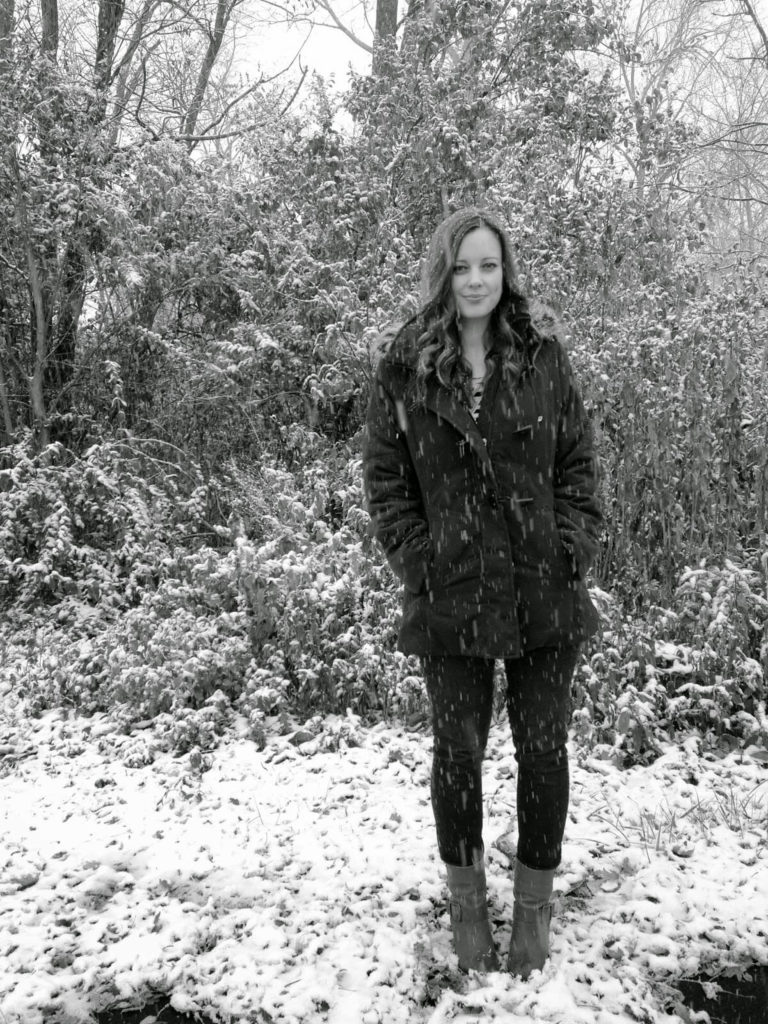 young woman standing in snow fall