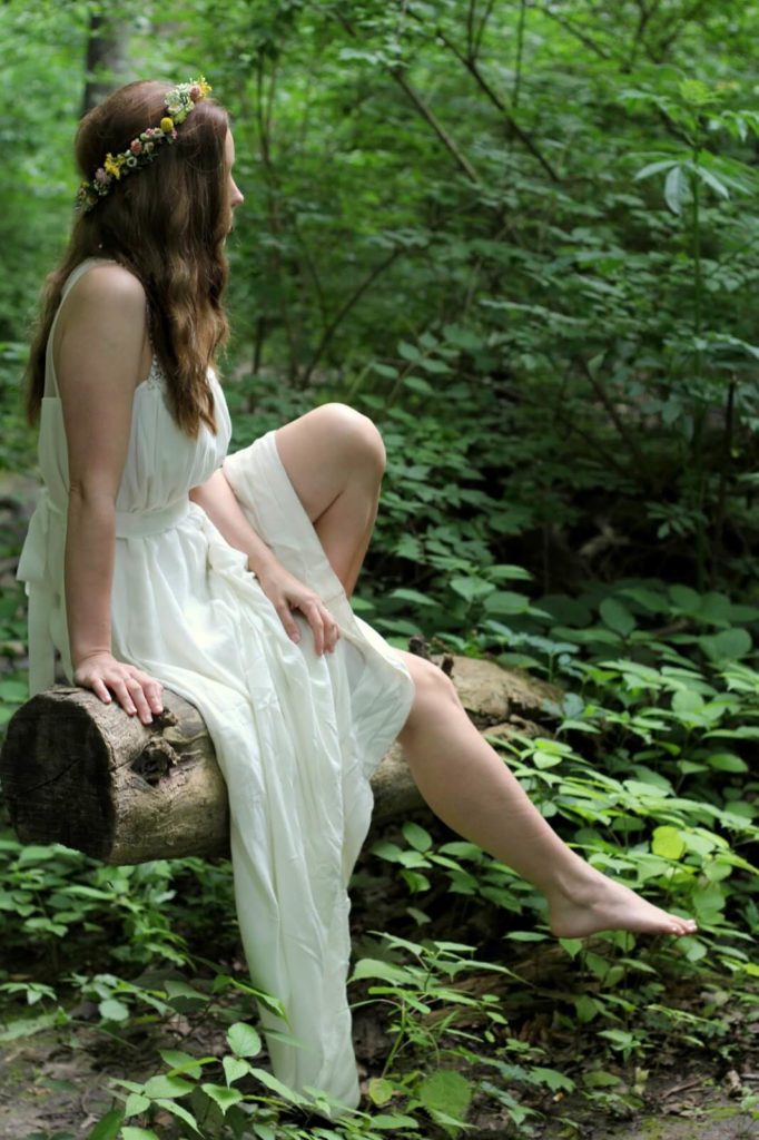 girl in white dress sitting on fallen log