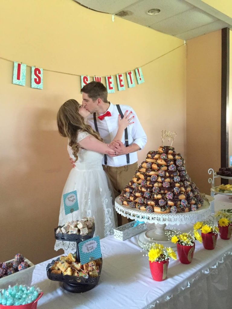 newly married couple kissing by donut cake