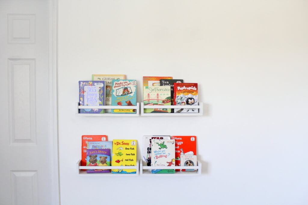4 little white bookshelves on the wall with kids books