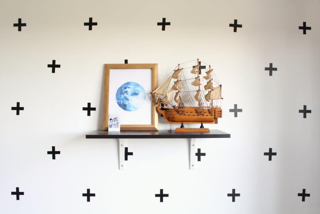 toy sail boat and moon picture on shelf with washi tape plus signs on wall