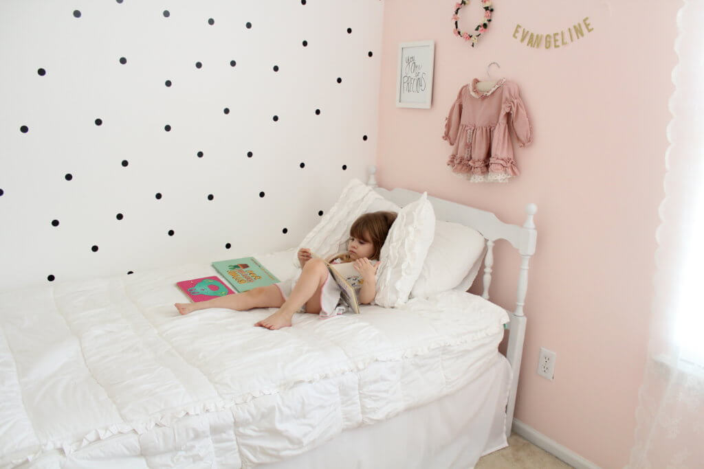 little girl reading books on bed