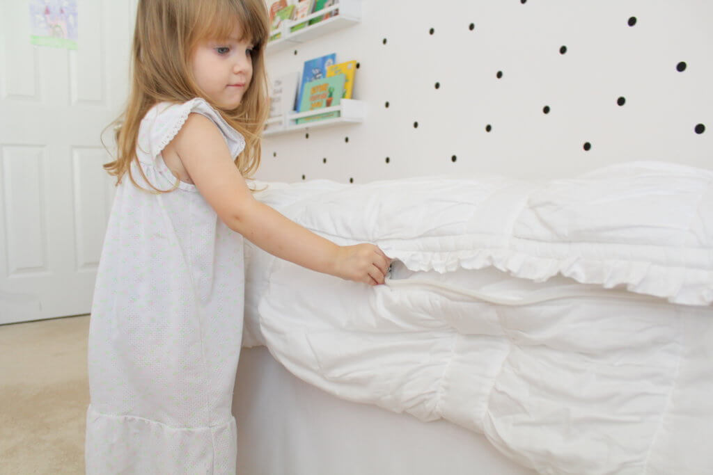 little girl zipping up bed sheets