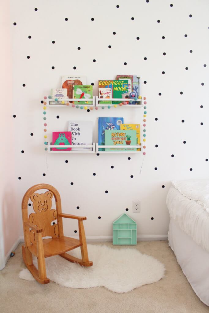 little white bookshelves on wall with children's books
